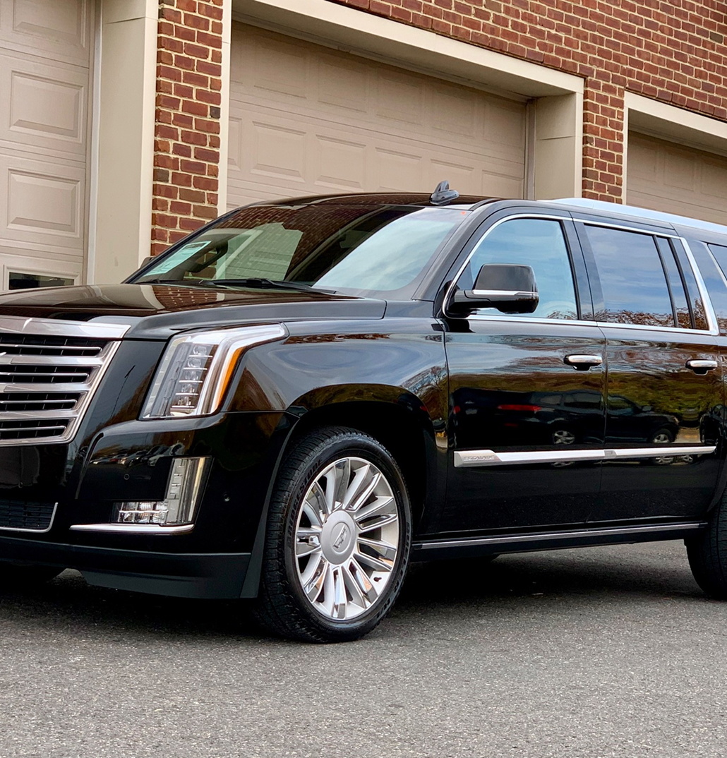 A picture of a Caddillac Escalade ESV in front of a brick building